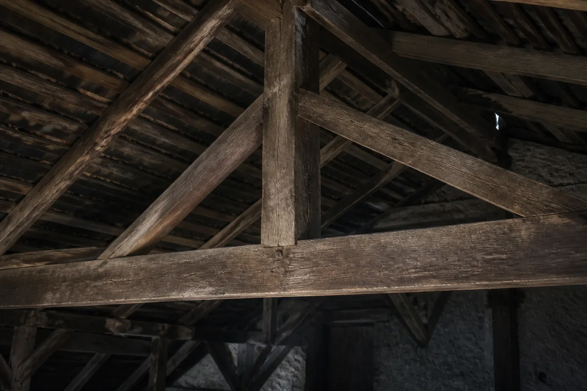 Assemblage de charpente ancienne en bois, entrait et poinçon dans une grange jurassienne