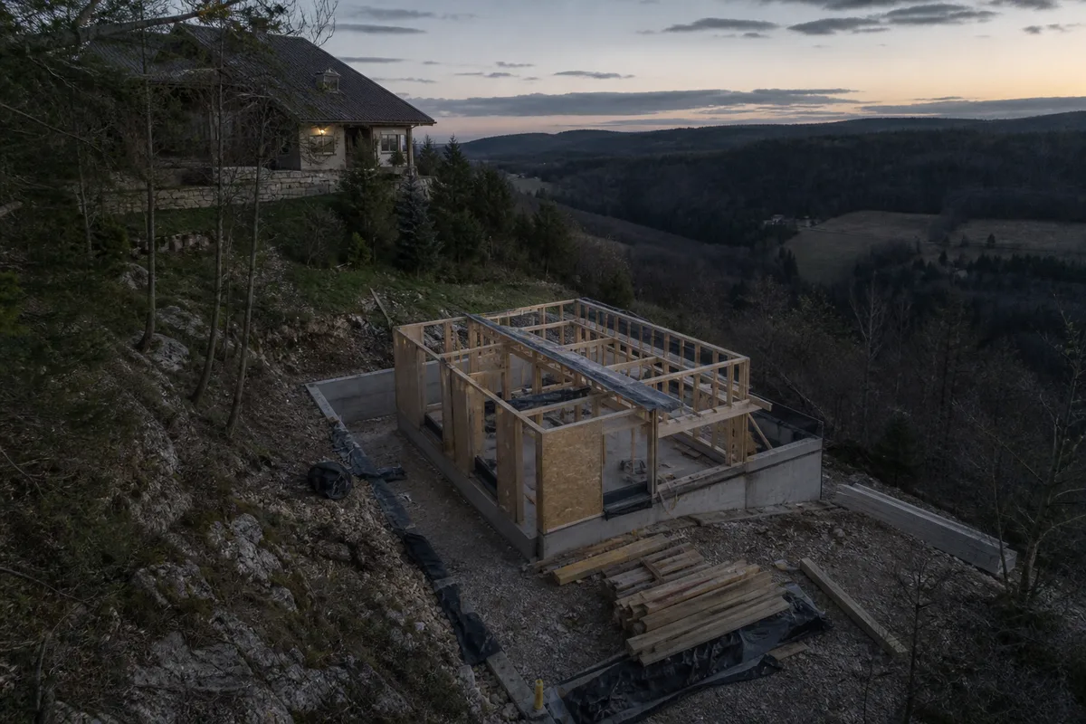 Chantier d&rsquo;extension à ossature bois posée en contrebas d&rsquo;une maison de montagne
